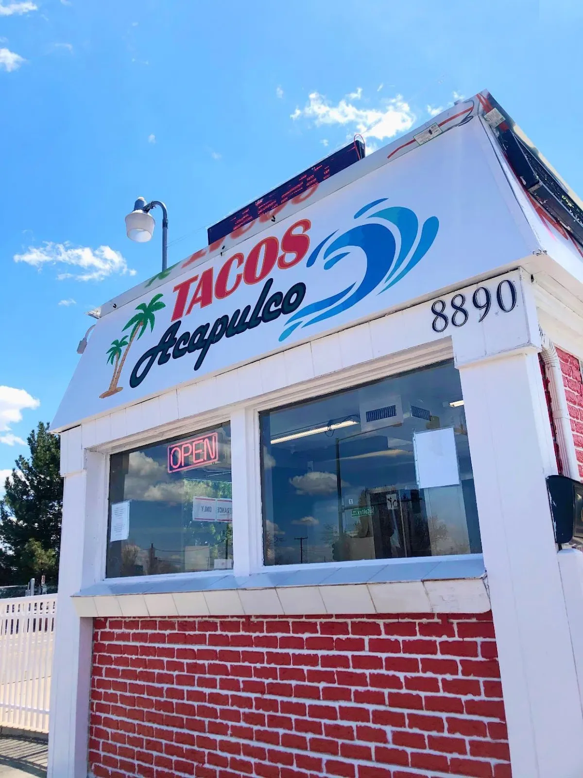 Tacos Acapulco sign with a red palm tree, a blue wave, and a neon Open light on East Colfax