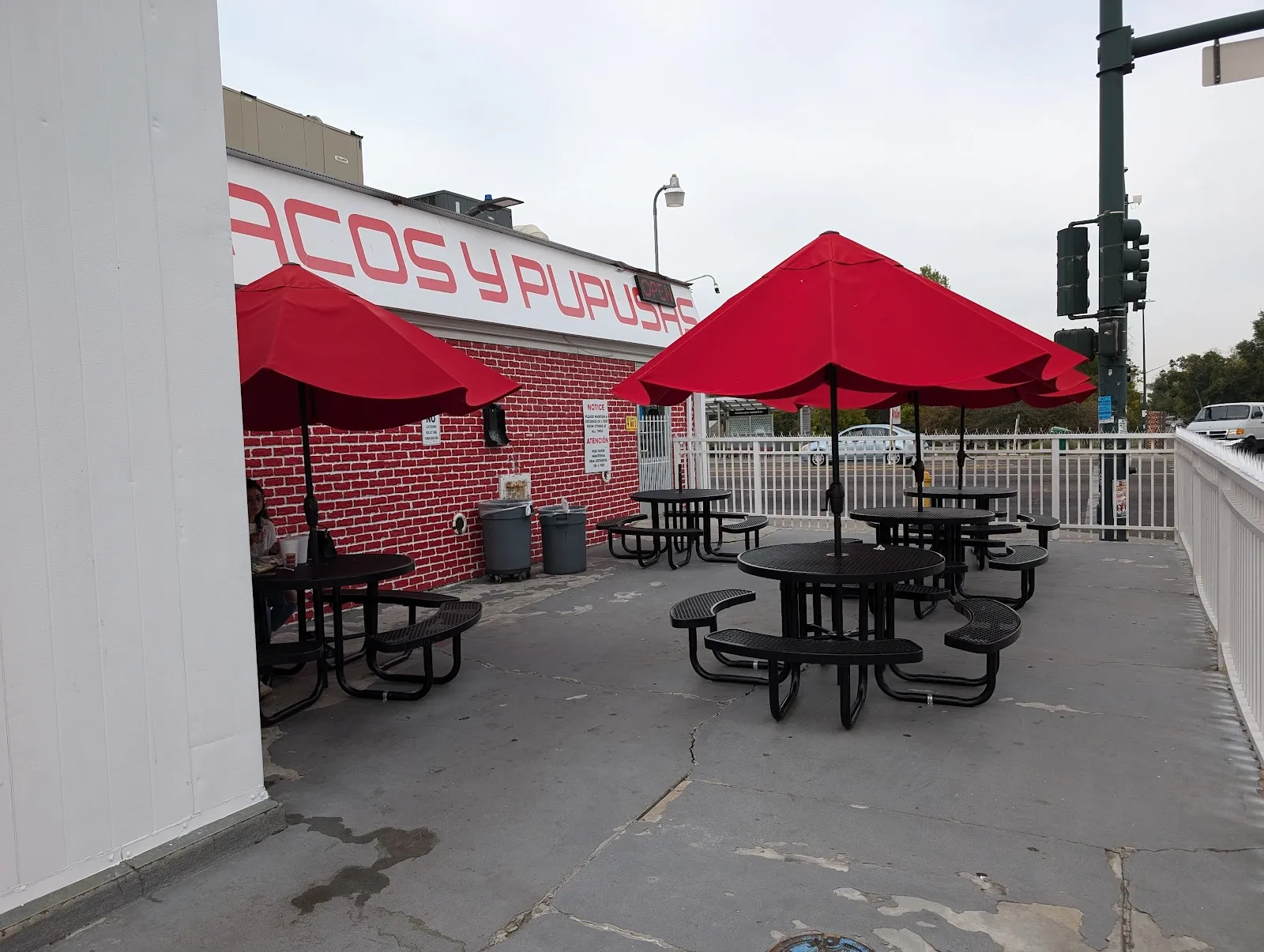 Red patio umbrellas over black picnic tables outside Tacos Acapulco