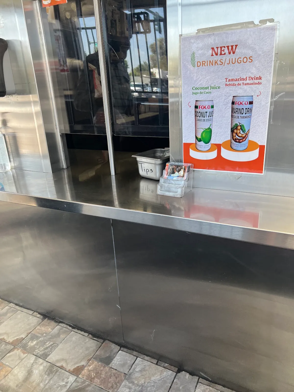 Stainless order window with a sign for new coconut and tamarind drinks