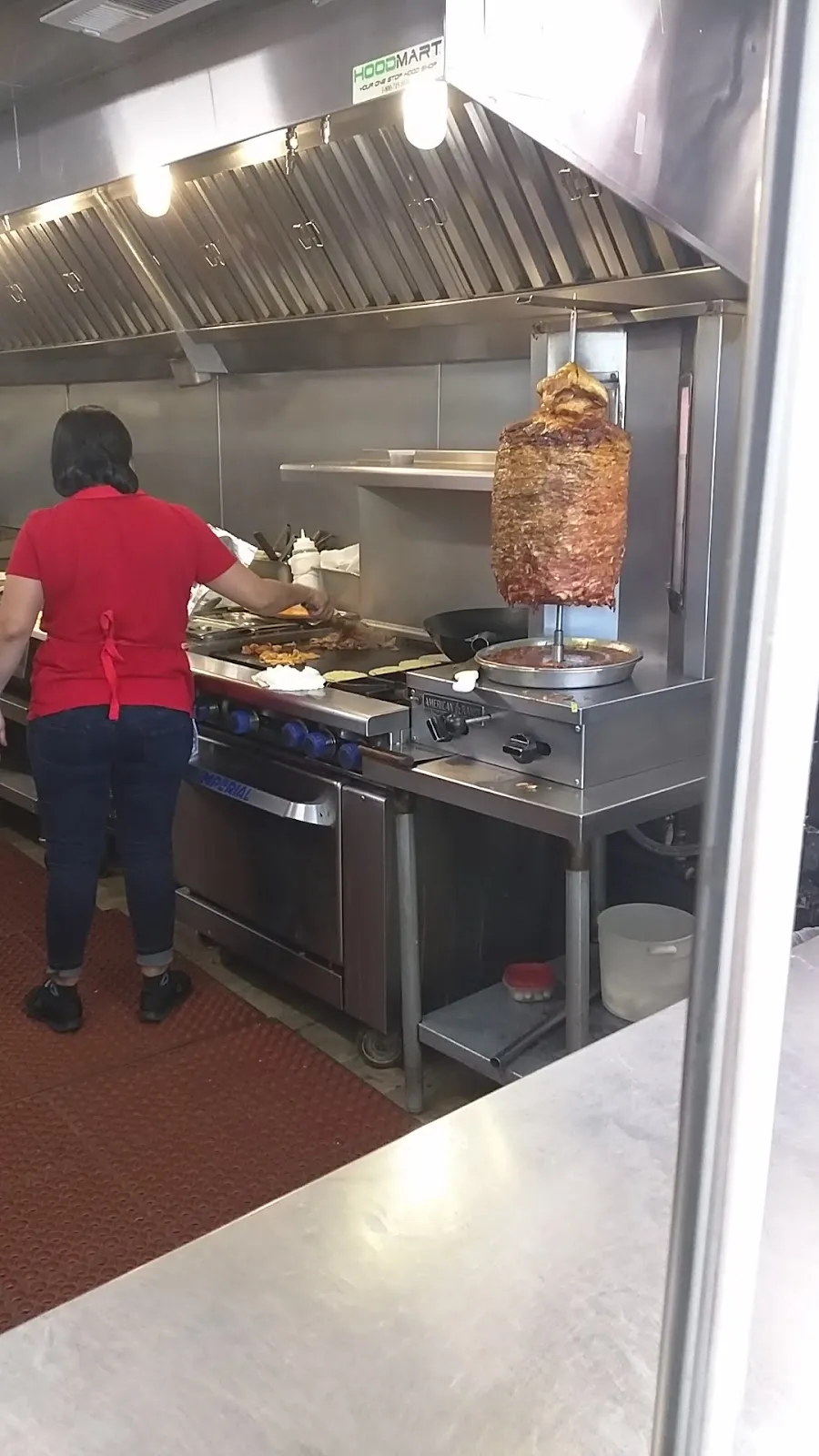 Cook tending the al pastor trompo spit in the Tacos Acapulco kitchen